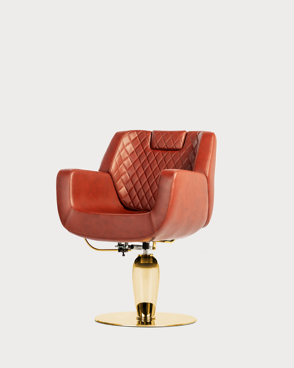 A professional hairdressing chair with blush pink upholstery and a gold-colored chrome base.